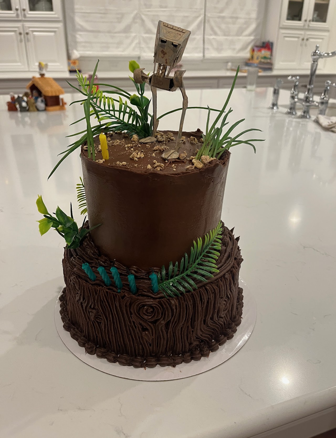 Chocolate cake with tree-bark textured buttercream piping and a sculpted AT-ST walker topper surrounded by greenery