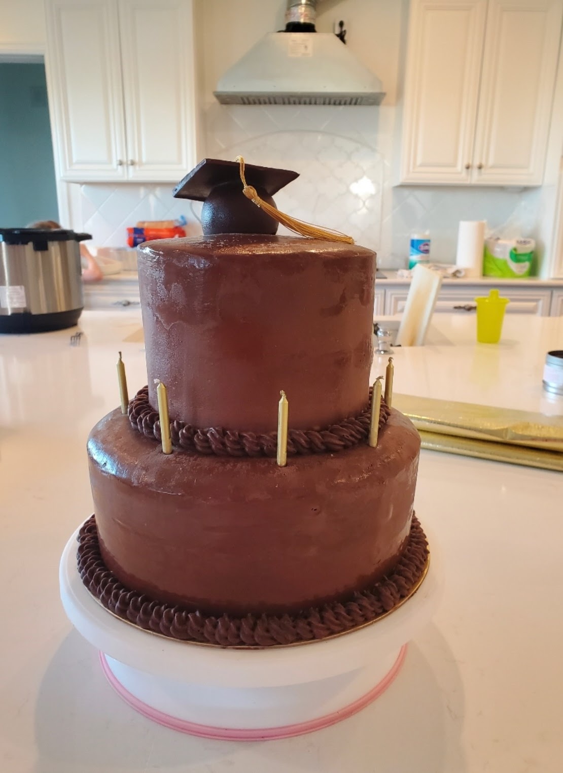 Two-tier glossy chocolate ganache cake with a sculpted chocolate graduation cap and tassel topper