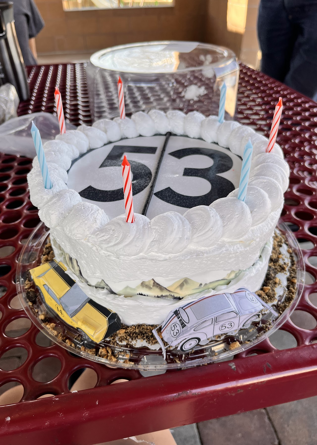 White scalloped buttercream cake with a printed number 53 design and custom car cutout toppers